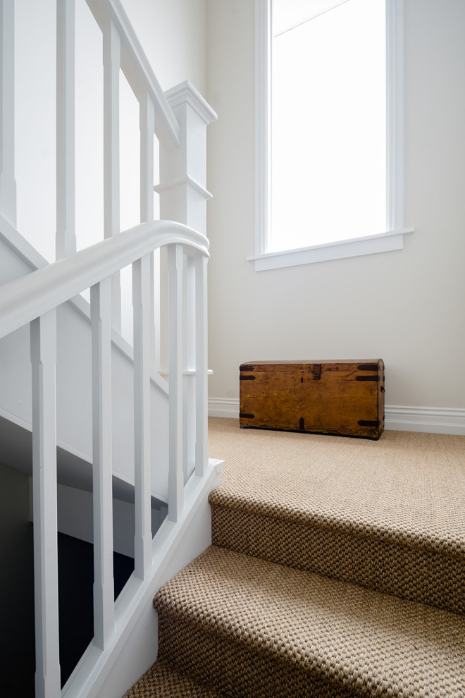 Cette photo montre un escalier en U de taille moyenne avec des marches en moquette, des contremarches en moquette et un garde-corps en bois.