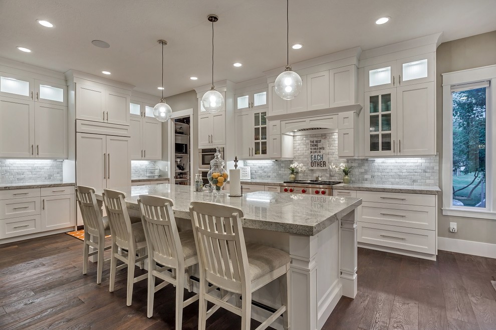 Large arts and crafts open plan kitchen in Salt Lake City with an undermount sink, recessed-panel cabinets, white cabinets, granite benchtops, multi-coloured splashback, stone tile splashback, stainless steel appliances, dark hardwood floors, with island and brown floor.