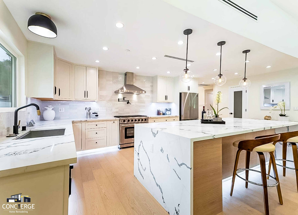 Example of a large country l-shaped open concept kitchen design in Los Angeles with shaker cabinets, beige cabinets, quartz countertops, white backsplash, porcelain backsplash, stainless steel appliances, an island and white countertops