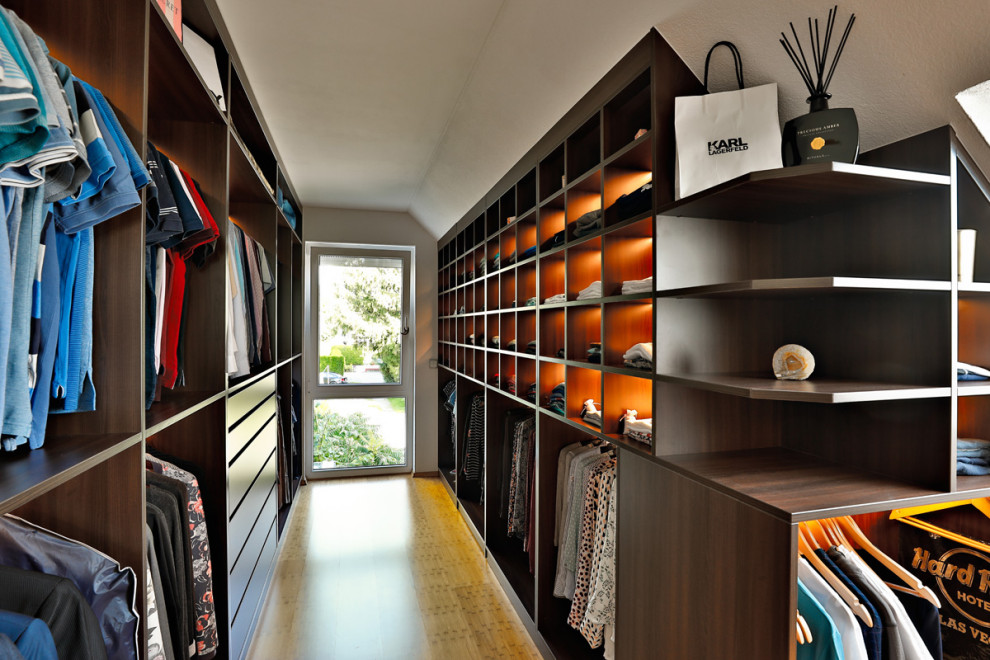 Photo of an expansive modern walk-in wardrobe in Stuttgart with open cabinets, bamboo floors and brown floor.