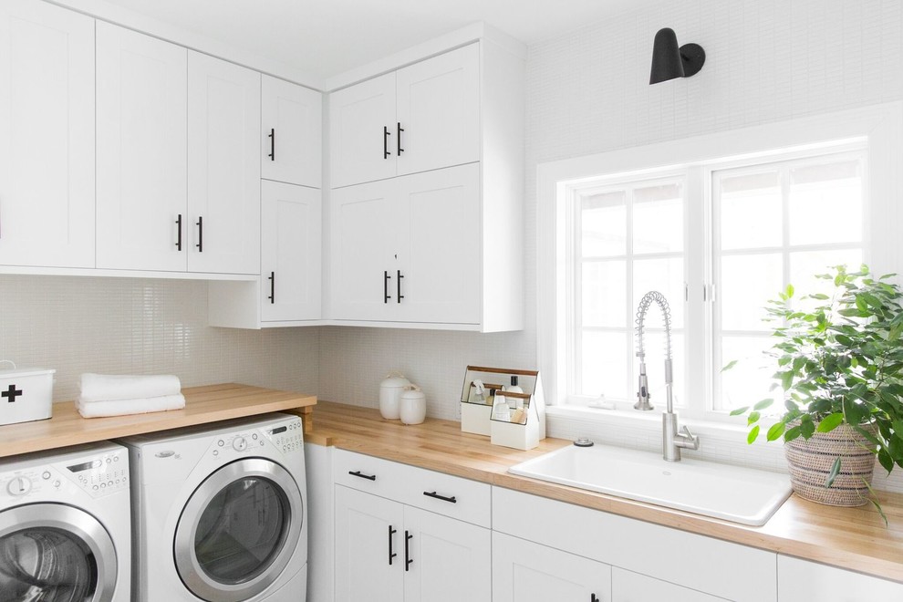 Design ideas for a large transitional l-shaped dedicated laundry room in Salt Lake City with shaker cabinets, a drop-in sink, white cabinets, wood benchtops, white walls, a side-by-side washer and dryer and beige benchtop.