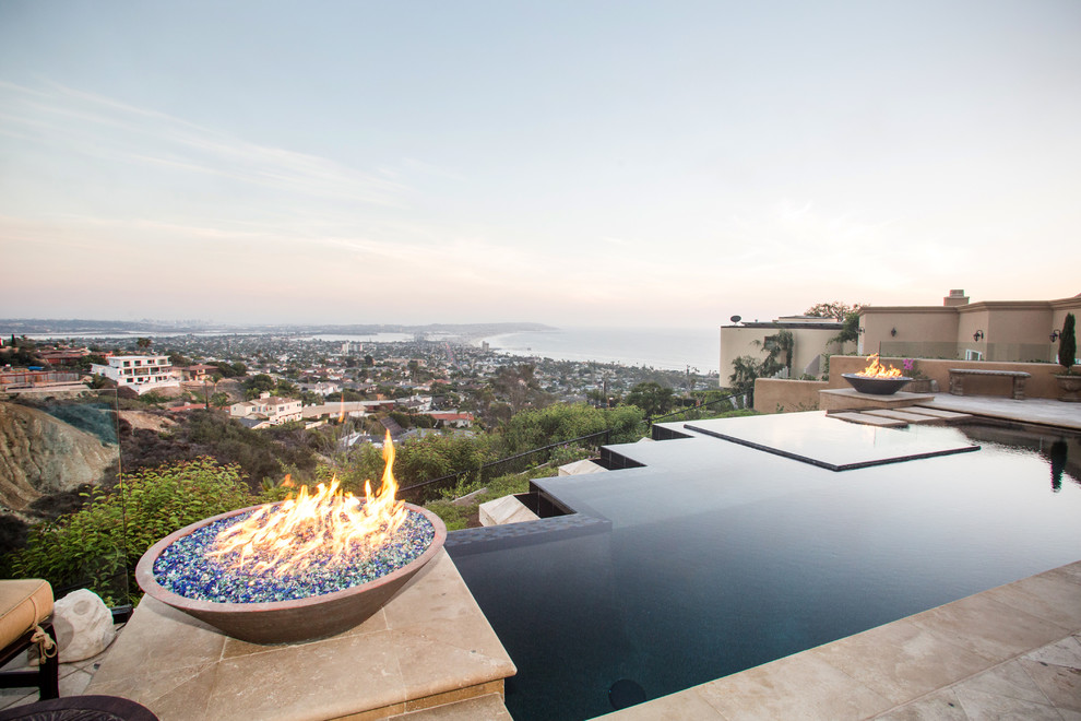 Photo of a large contemporary backyard custom-shaped infinity pool in San Diego with natural stone pavers.
