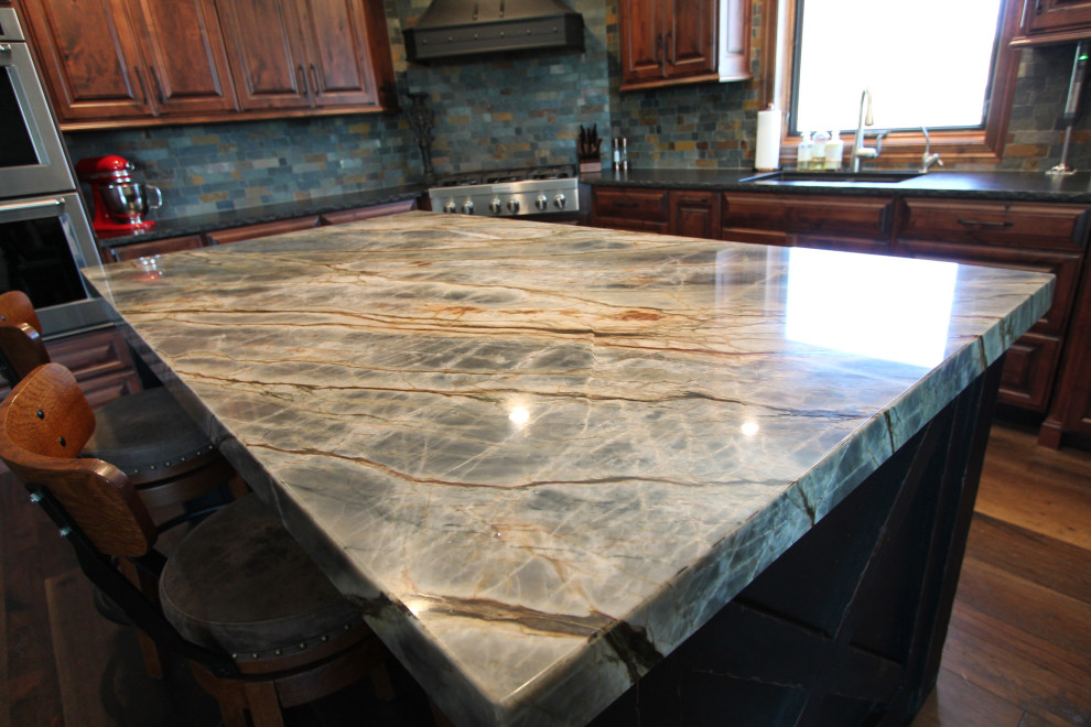 Kitchen - large rustic medium tone wood floor and brown floor kitchen idea with an undermount sink, raised-panel cabinets, medium tone wood cabinets, granite countertops, multicolored backsplash, stone tile backsplash, paneled appliances, an island and multicolored countertops
