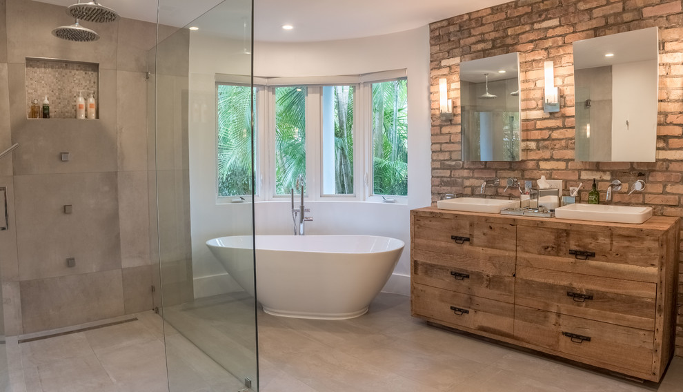 Photo of a large industrial master bathroom in Miami with light wood cabinets, a freestanding tub, an open shower, white walls, porcelain floors, a drop-in sink, wood benchtops, grey floor and a hinged shower door.