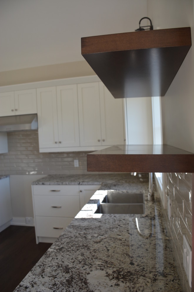 Mid-sized transitional u-shaped light wood floor eat-in kitchen photo in Toronto with a double-bowl sink, shaker cabinets, white cabinets, granite countertops, gray backsplash, subway tile backsplash, stainless steel appliances and an island