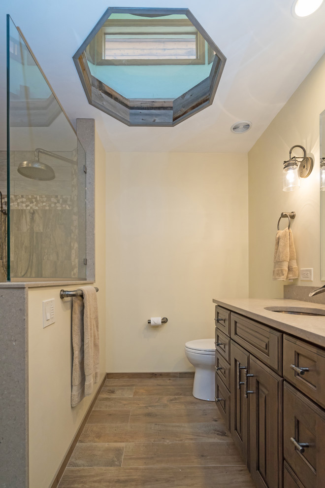 Large country master bathroom in Philadelphia with raised-panel cabinets, distressed cabinets, a curbless shower, a two-piece toilet, gray tile, porcelain tile, beige walls, porcelain floors, engineered quartz benchtops, brown floor, an open shower and beige benchtops.