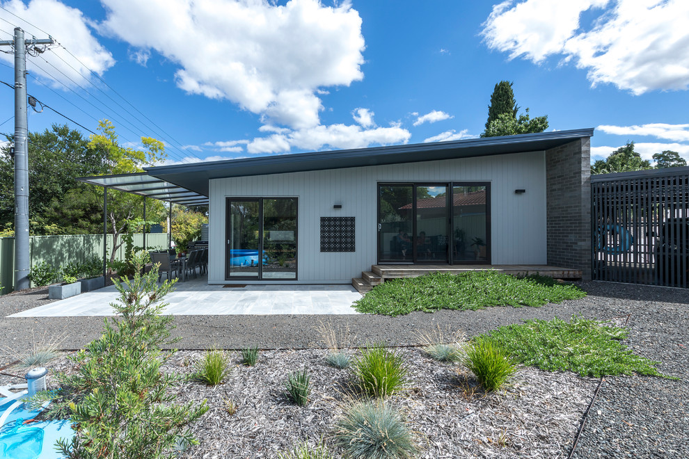 Design ideas for a small contemporary one-storey brick grey house exterior in Canberra - Queanbeyan with a flat roof and a metal roof.