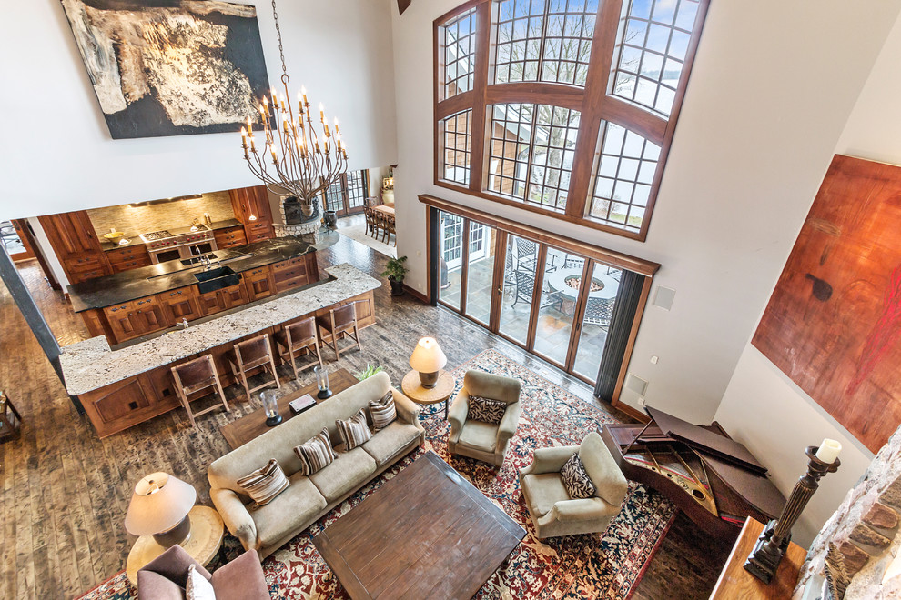 This is an example of an expansive country open concept living room in Milwaukee with white walls, dark hardwood floors, a standard fireplace, a stone fireplace surround and a music area.