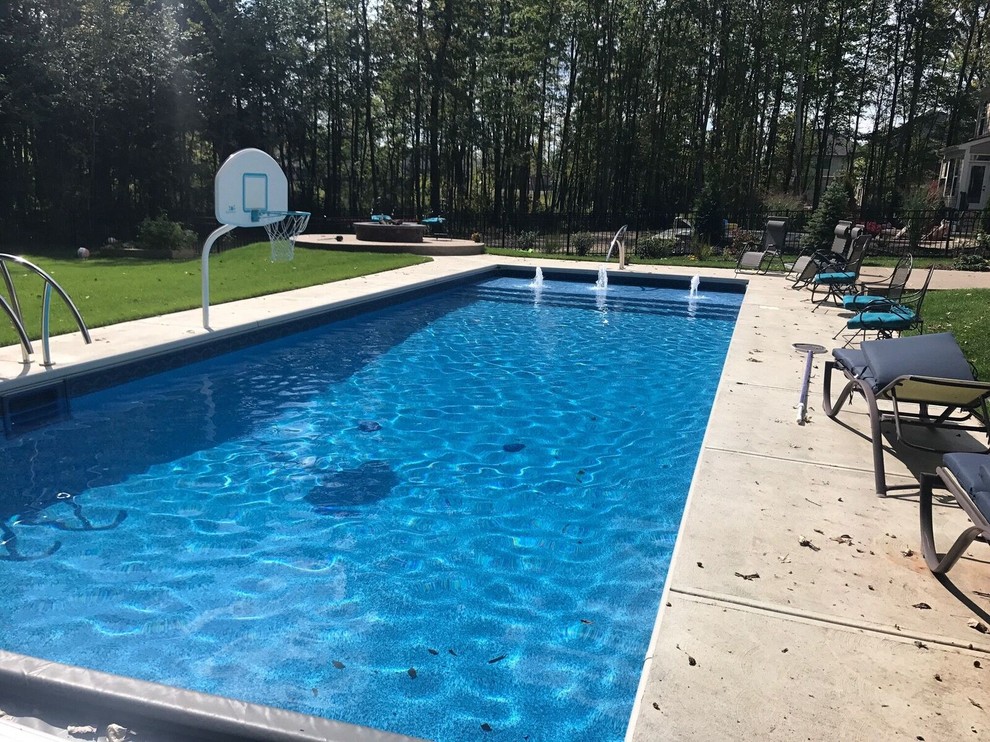 This is an example of a mid-sized modern backyard rectangular lap pool in Indianapolis with a water feature and stamped concrete.
