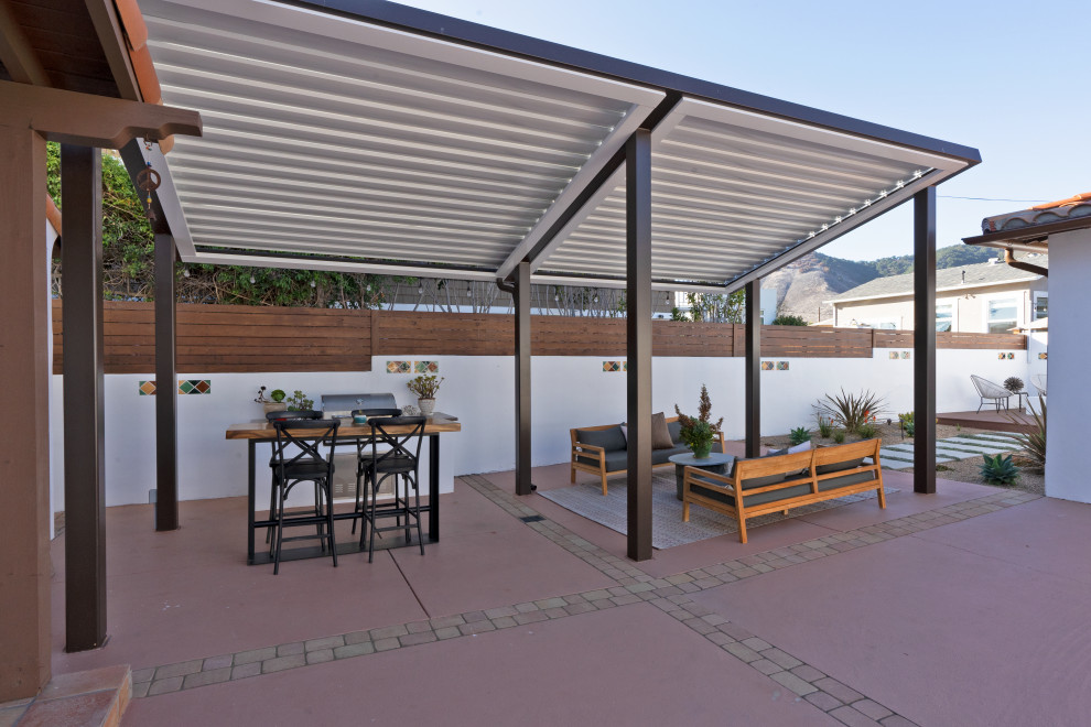 This is an example of a mid-sized mediterranean backyard patio in San Luis Obispo with an outdoor kitchen, concrete slab and a pergola.