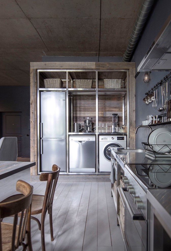 Cette image montre une petite cuisine ouverte linéaire en inox avec un placard sans porte, un plan de travail en inox, un électroménager en acier inoxydable, parquet peint, aucun îlot et un sol blanc.