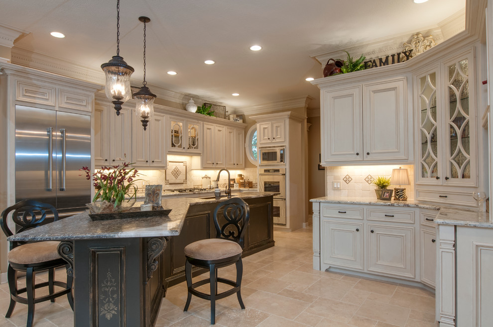 Enclosed kitchen - mid-sized transitional u-shaped travertine floor and beige floor enclosed kitchen idea in Houston with an island, a farmhouse sink, recessed-panel cabinets, white cabinets, granite countertops, beige backsplash, stone tile backsplash and stainless steel appliances
