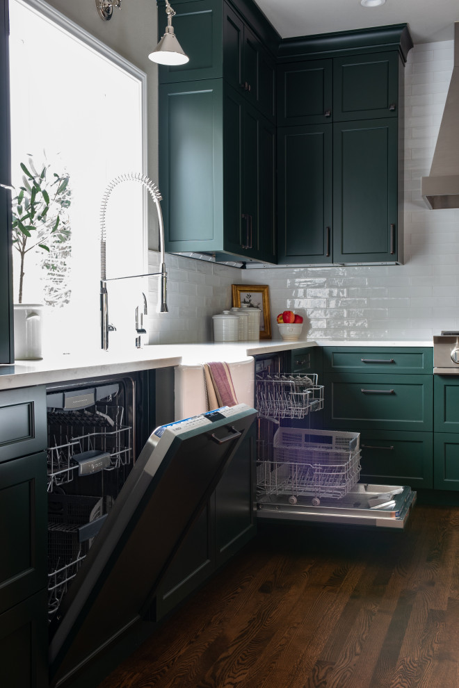 Enclosed kitchen - large transitional u-shaped dark wood floor and brown floor enclosed kitchen idea in Seattle with a farmhouse sink, recessed-panel cabinets, green cabinets, quartz countertops, white backsplash, porcelain backsplash, stainless steel appliances, an island and white countertops
