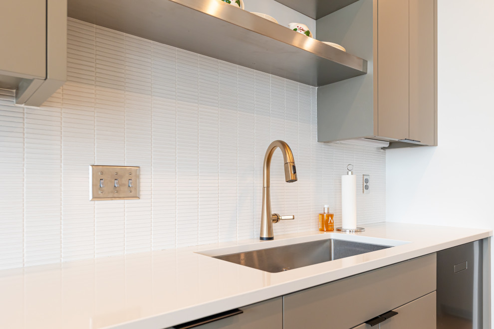 This is an example of a medium sized contemporary l-shaped kitchen/diner in Minneapolis with a submerged sink, flat-panel cabinets, brown cabinets, engineered stone countertops, white splashback, ceramic splashback, stainless steel appliances, laminate floors, an island, brown floors and white worktops.