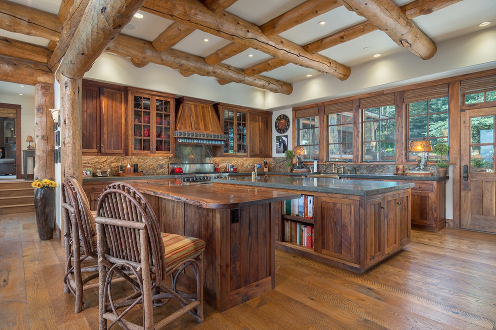 Country l-shaped eat-in kitchen in Other with a farmhouse sink, shaker cabinets, medium wood cabinets, wood benchtops, grey splashback, stainless steel appliances, medium hardwood floors, multiple islands and brown floor.