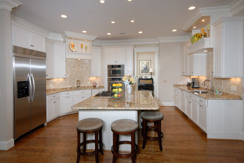 Design ideas for a large traditional u-shaped open plan kitchen in Cincinnati with an undermount sink, shaker cabinets, white cabinets, granite benchtops, beige splashback, stone tile splashback, stainless steel appliances, medium hardwood floors and with island.