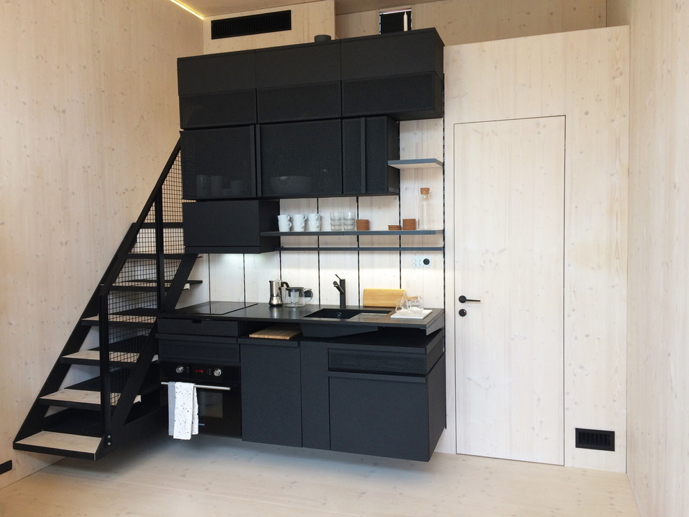 Photo of a small scandinavian single-wall kitchen in Essex with flat-panel cabinets, black cabinets, black appliances and light hardwood floors.