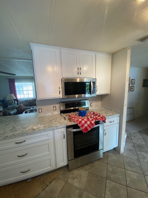 Inspiration for a large galley eat-in kitchen remodel with shaker cabinets, white cabinets, laminate countertops, a peninsula and white countertops