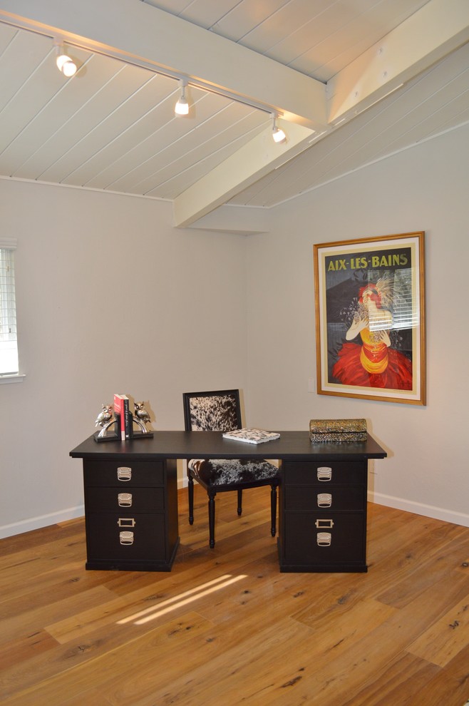 This is an example of a small transitional study room in San Francisco with white walls, medium hardwood floors and a freestanding desk.