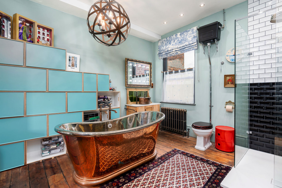 Eklektisches Badezimmer mit hellen Holzschränken, freistehender Badewanne, schwarz-weißen Fliesen, blauer Wandfarbe, dunklem Holzboden, Aufsatzwaschbecken, braunem Boden, offener Dusche, weißer Waschtischplatte und Einzelwaschbecken in Manchester