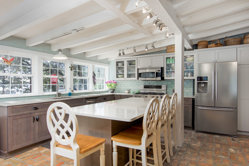 Mid-sized country l-shaped eat-in kitchen in Miami with quartz benchtops, subway tile splashback, with island, an undermount sink, shaker cabinets, white cabinets, green splashback, stainless steel appliances, brick floors and red floor.