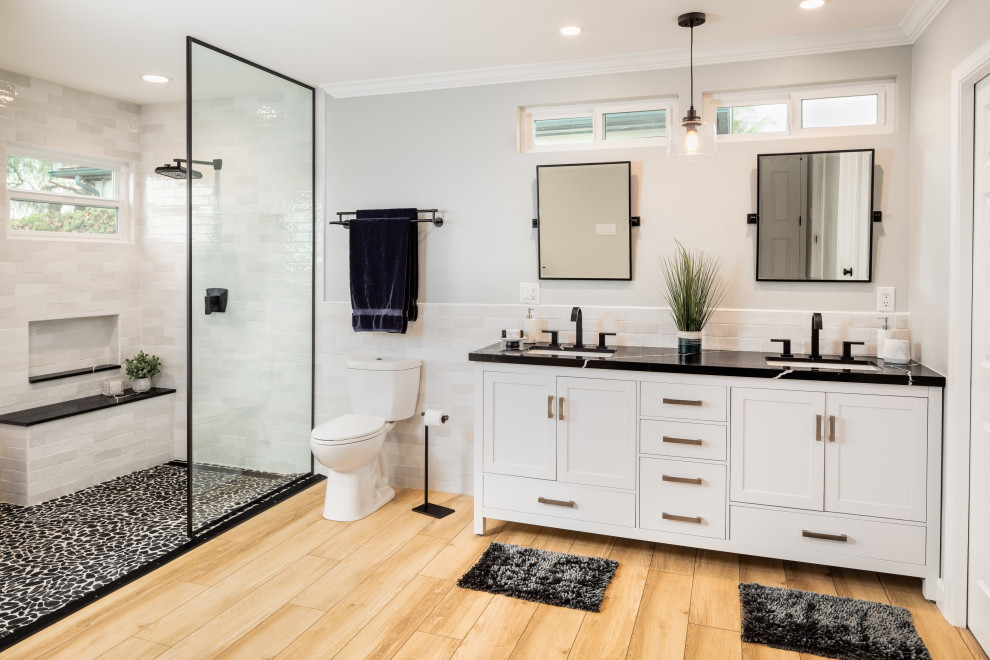 Transitional bathroom in San Diego with shaker cabinets, white cabinets, an alcove shower, white tile, grey walls, light hardwood floors, an undermount sink, beige floor, an open shower, black benchtops, a double vanity, a freestanding vanity, a niche and a shower seat.