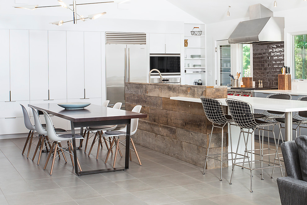 Eat-in kitchen - contemporary porcelain tile eat-in kitchen idea in New York with solid surface countertops, ceramic backsplash, stainless steel appliances, flat-panel cabinets, white cabinets, brown backsplash and an island