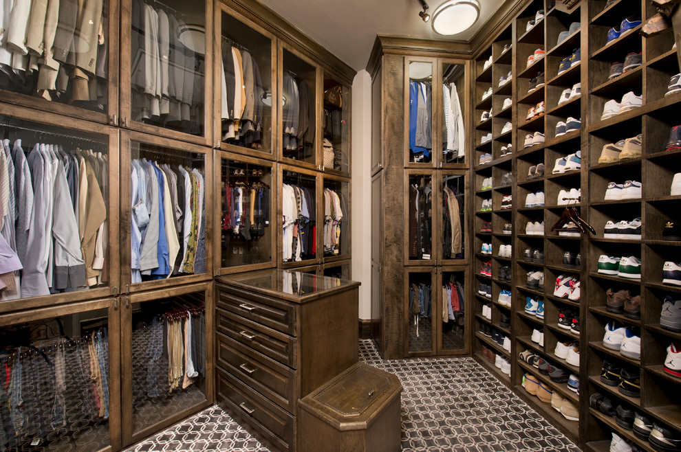 This is an example of a large traditional men's dressing room in Houston with glass-front cabinets, dark wood cabinets and multi-coloured floor.
