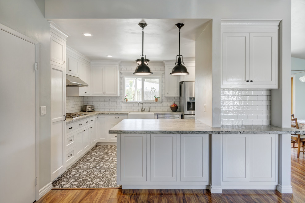 Small country galley kitchen pantry in San Diego with a farmhouse sink, shaker cabinets, white cabinets, granite benchtops, white splashback, porcelain splashback, stainless steel appliances, ceramic floors and a peninsula.