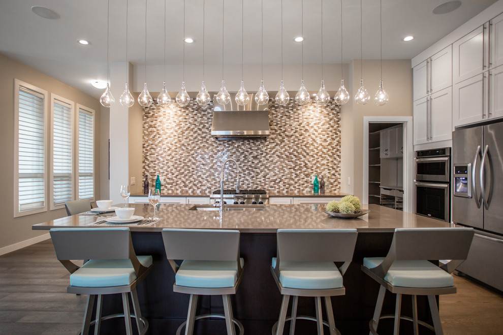 Inspiration for a mid-sized modern l-shaped dark wood floor kitchen remodel with an undermount sink, shaker cabinets, white cabinets, beige backsplash, mosaic tile backsplash, stainless steel appliances and an island