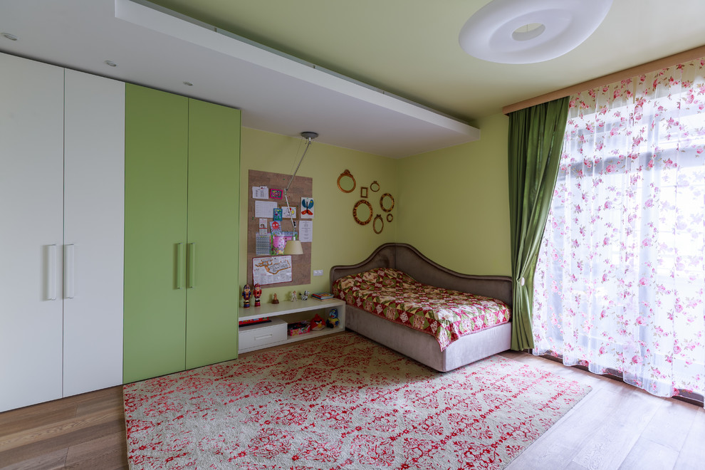 This is an example of a contemporary kids' bedroom for girls in Moscow with green walls and carpet.