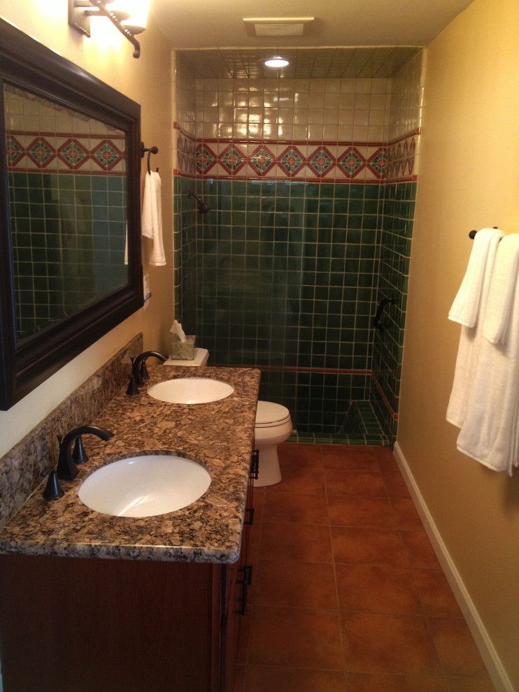 Mid-sized mediterranean 3/4 bathroom in Orange County with dark wood cabinets, an alcove shower, green tile, multi-coloured tile, ceramic tile, brown walls, terra-cotta floors, an undermount sink, granite benchtops, brown floor, an open shower and brown benchtops.