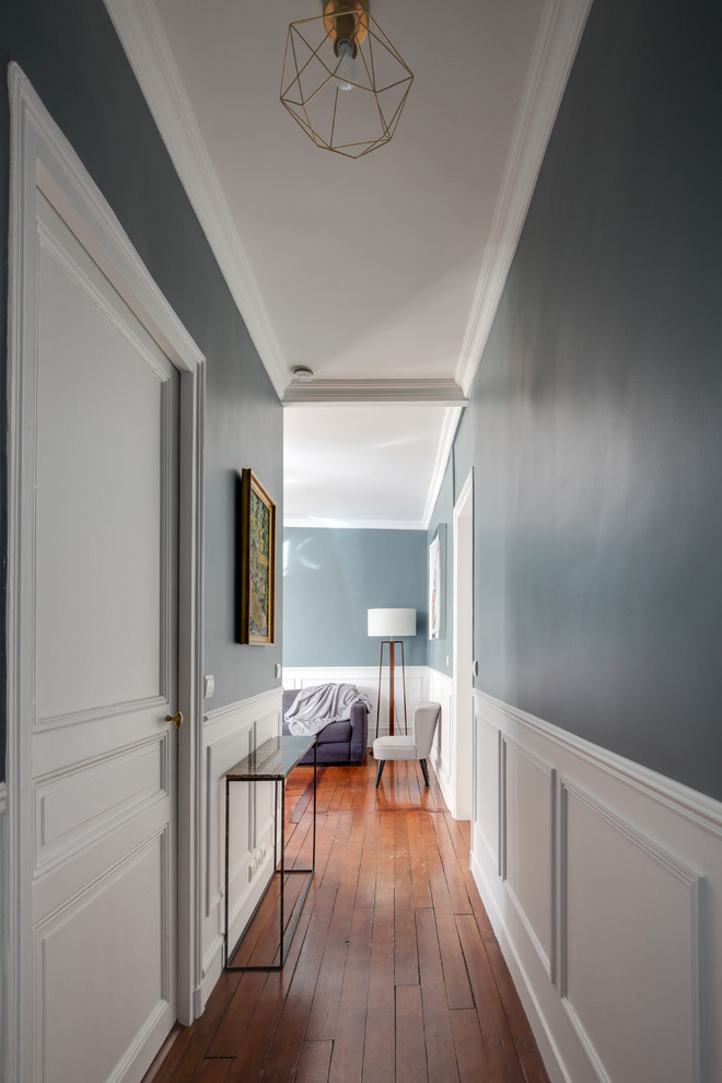 Photo of a mid-sized transitional hallway in Paris with blue walls, dark hardwood floors and brown floor.