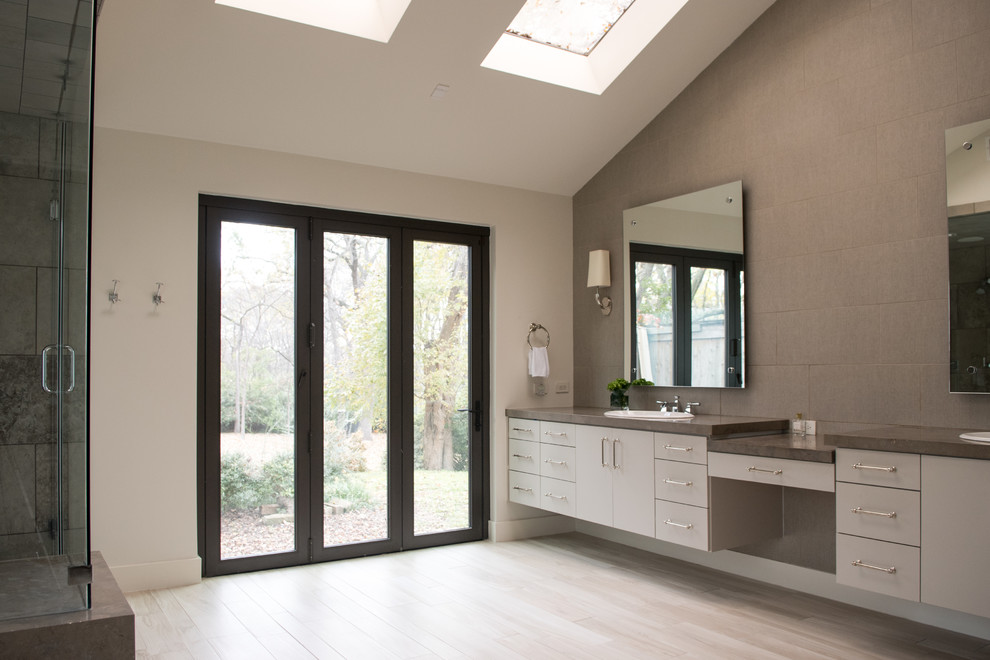 Drop-in bathtub - mid-sized transitional master gray tile and cement tile light wood floor and beige floor drop-in bathtub idea in Dallas with flat-panel cabinets, gray cabinets, gray walls, a drop-in sink, concrete countertops and a hinged shower door