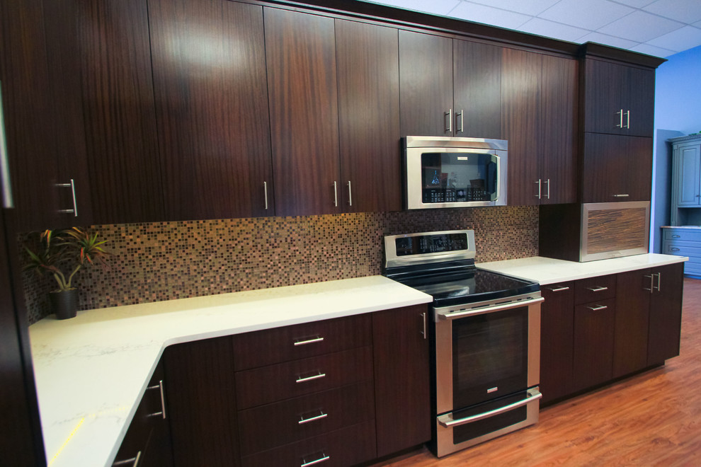 Example of a mid-sized transitional l-shaped eat-in kitchen design in Seattle with flat-panel cabinets, dark wood cabinets, granite countertops, multicolored backsplash, glass tile backsplash, stainless steel appliances and an island