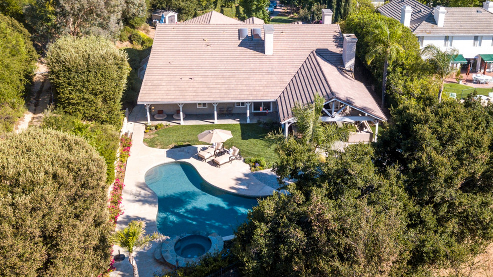 Example of a huge transitional backyard brick and kidney-shaped natural pool design in Los Angeles