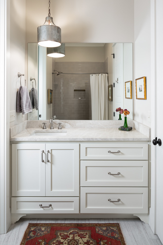 This is an example of a small traditional kids bathroom in Birmingham with recessed-panel cabinets, beige cabinets, an alcove tub, a corner shower, a two-piece toilet, grey walls, ceramic floors, an undermount sink, marble benchtops, grey floor, a shower curtain and beige benchtops.