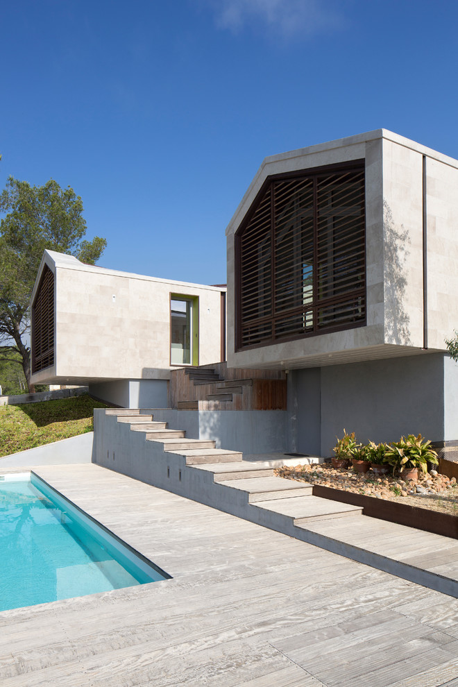 Mid-sized contemporary two-storey beige exterior in Montpellier with stone veneer and a gable roof.
