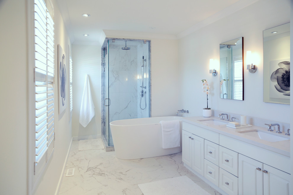 Inspiration for a mid-sized contemporary master gray tile, white tile and stone tile marble floor and white floor freestanding bathtub remodel in Toronto with white cabinets, white walls, raised-panel cabinets, an undermount sink and a hinged shower door