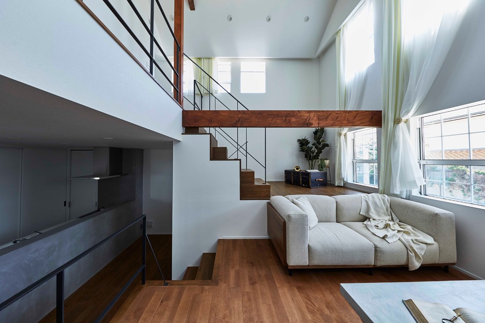 This is an example of a transitional living room in Nagoya with white walls, medium hardwood floors and brown floor.