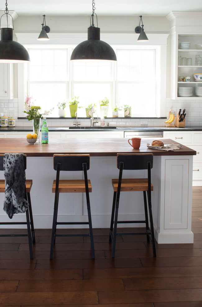 Inspiration for a large transitional l-shaped dark wood floor and brown floor eat-in kitchen remodel in Burlington with a single-bowl sink, shaker cabinets, white cabinets, soapstone countertops, white backsplash, ceramic backsplash, stainless steel appliances, an island and black countertops