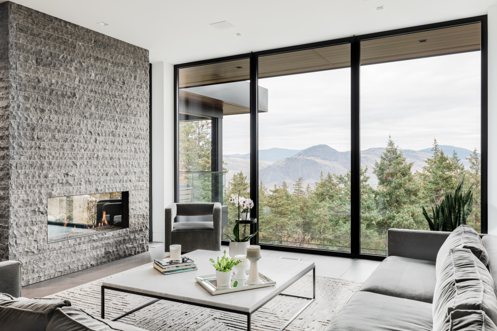 Mittelgroßes, Fernseherloses, Offenes Modernes Wohnzimmer mit weißer Wandfarbe, Porzellan-Bodenfliesen, Gaskamin, Kaminumrandung aus gestapelten Steinen und grauem Boden in Vancouver