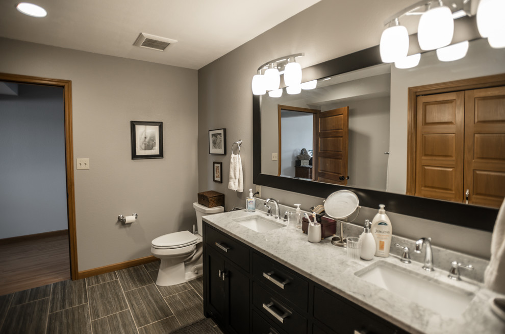 This is an example of a mid-sized transitional master bathroom in Other with flat-panel cabinets, dark wood cabinets, a two-piece toilet, gray tile, ceramic tile, grey walls, ceramic floors, an undermount sink and engineered quartz benchtops.