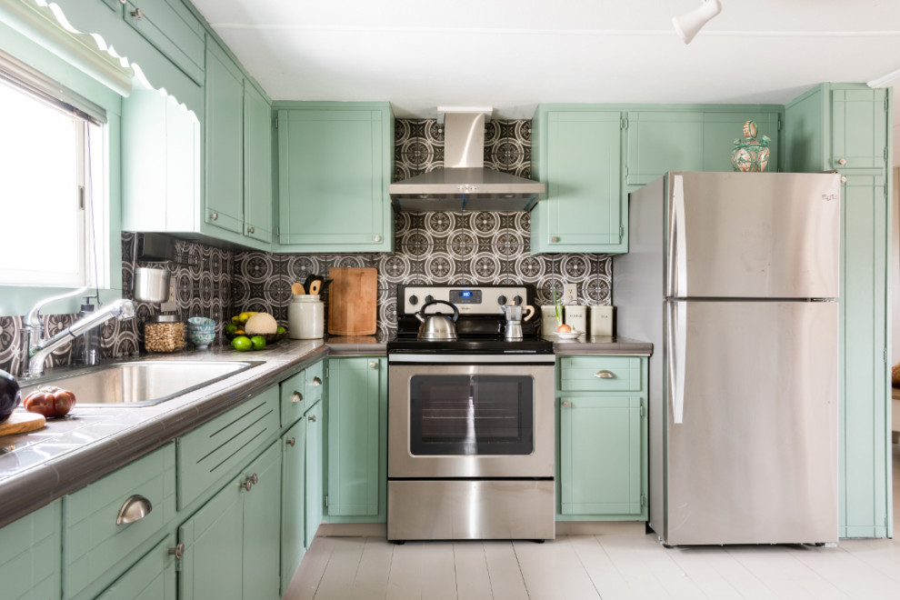 Photo of an eclectic eat-in kitchen in New York with a drop-in sink, green cabinets, tile benchtops, grey splashback, cement tile splashback, stainless steel appliances, painted wood floors, grey floor and grey benchtop.