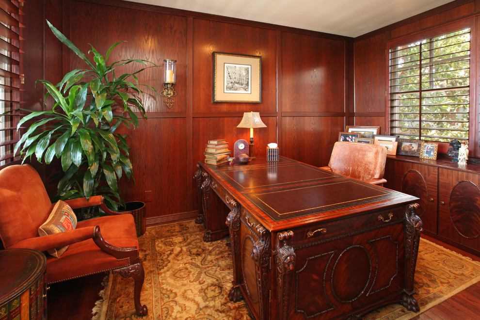This is an example of a traditional home office in Orange County with dark hardwood floors and a freestanding desk.