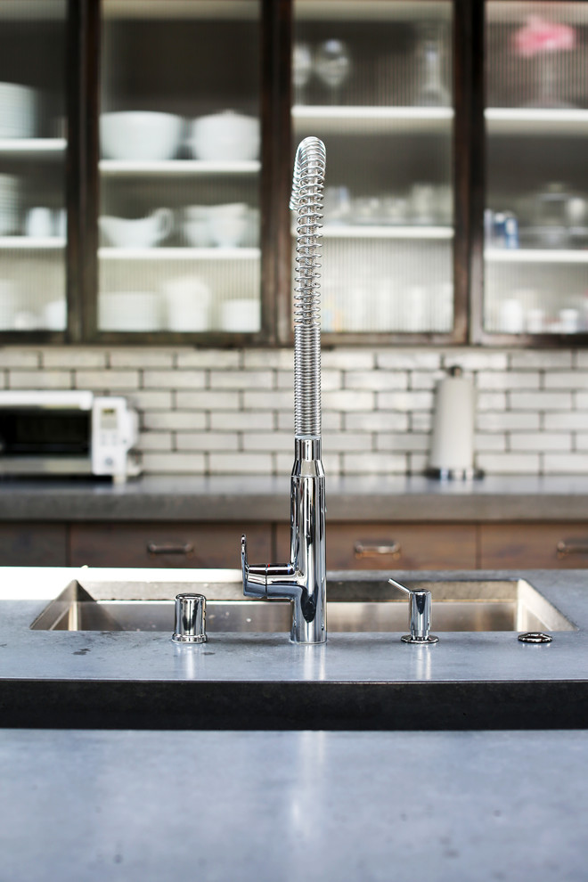 Large industrial u-shaped open plan kitchen in San Diego with with island, flat-panel cabinets, grey cabinets, concrete benchtops, white splashback, cement tile splashback, stainless steel appliances, an integrated sink and limestone floors.