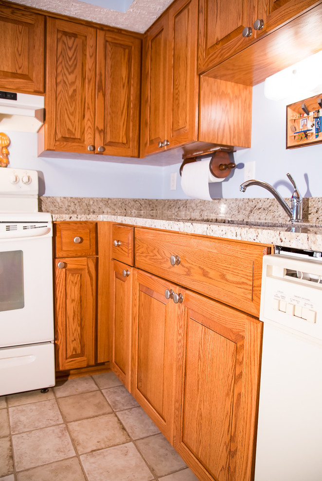Inspiration for a small rustic l-shaped kitchen remodel in Baltimore with a double-bowl sink, raised-panel cabinets, medium tone wood cabinets, blue backsplash, white appliances and no island