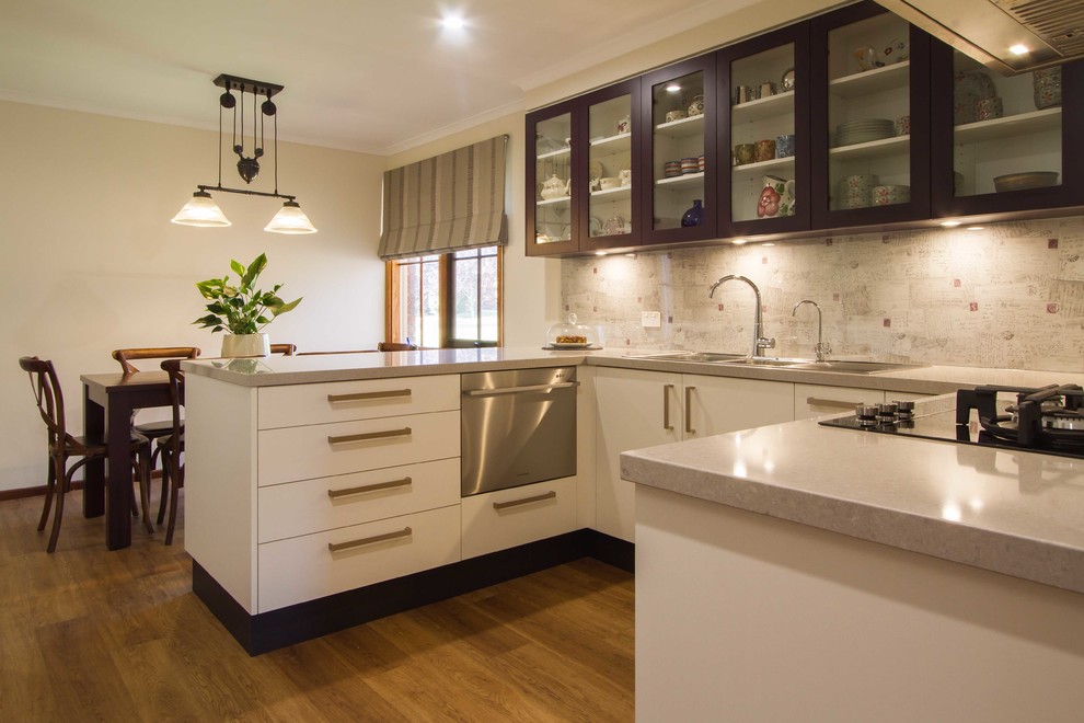 This is an example of a mid-sized contemporary u-shaped eat-in kitchen in Melbourne with flat-panel cabinets, white cabinets, quartz benchtops, stainless steel appliances and a peninsula.