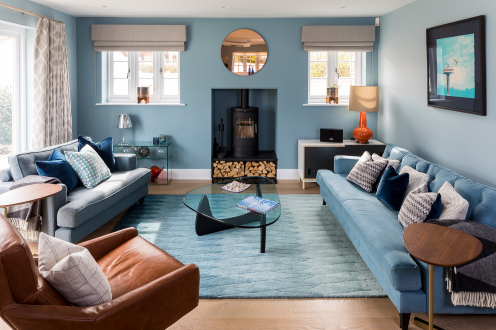 Diseño de salón contemporáneo con paredes azules, suelo de madera en tonos medios, estufa de leña y suelo marrón