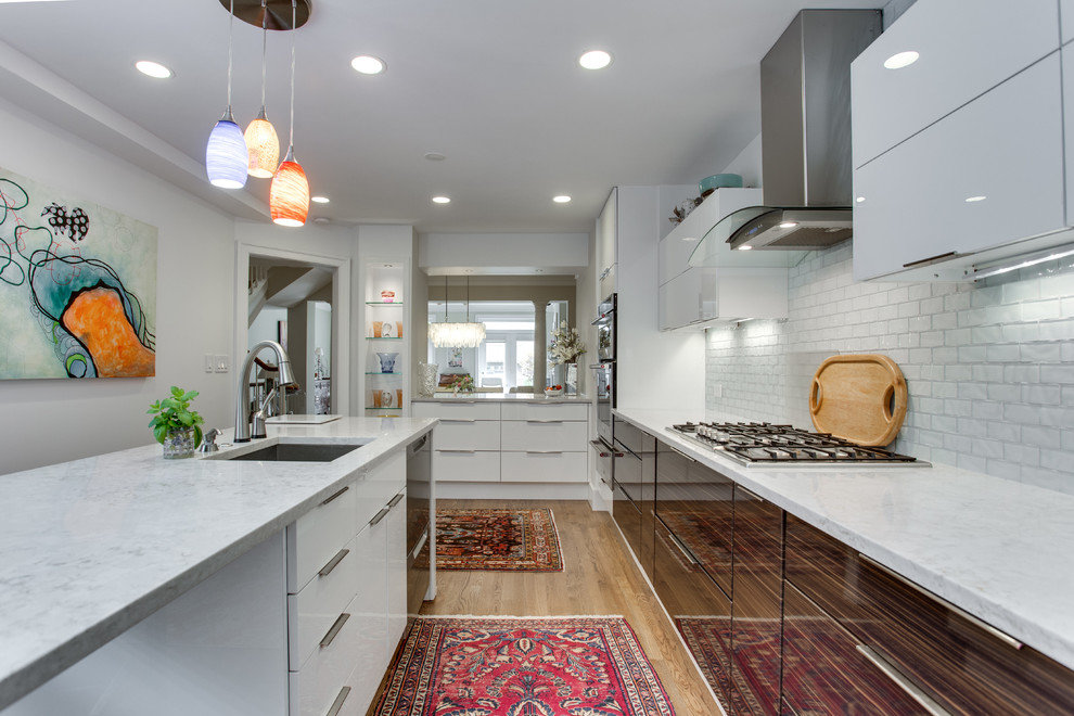 Design ideas for a mid-sized modern kitchen in DC Metro with an undermount sink, flat-panel cabinets, white splashback, stainless steel appliances and medium hardwood floors.